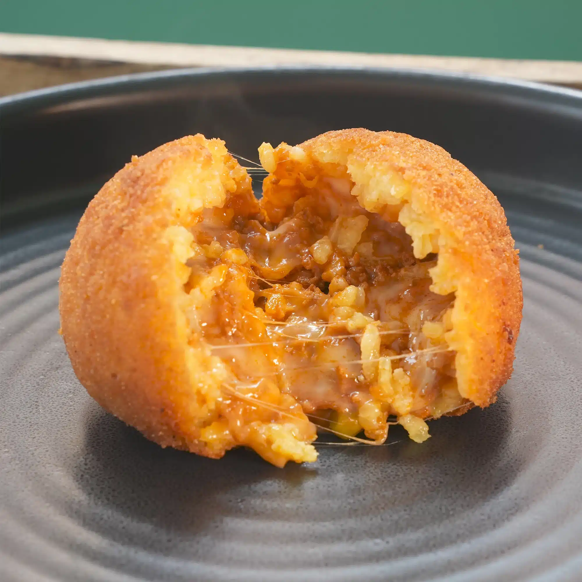 Arancino siciliano al ragù aperto, con formaggio a pasta filata che fila | Braceriadeigoti